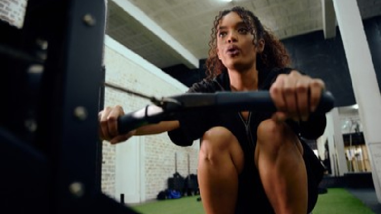 A person exercises on a rowing machine in the gym.