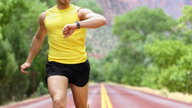 An athlete checks their fitness tracking watch on an outdoor LISS cardio session.