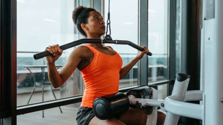 A person doing lat exercises with a lat pulldown machine.