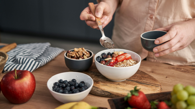 A person adding seed powder to a bowl of cereal.