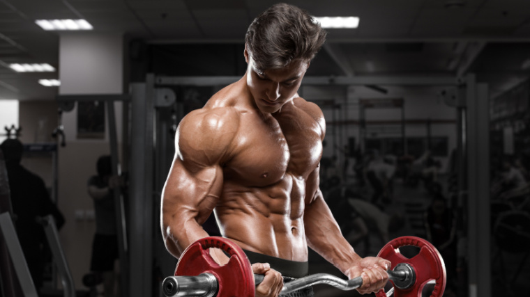 A muscular person working out in the gym with a barbell.