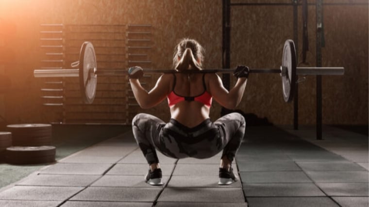 A person doing a barbell back squat.