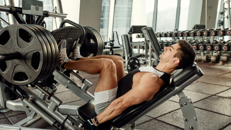 A person doing workout on a leg press machine inside the gym