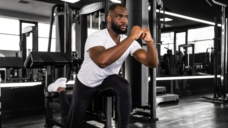 Strong sportsman doing Bulgarian lunges in a gym.