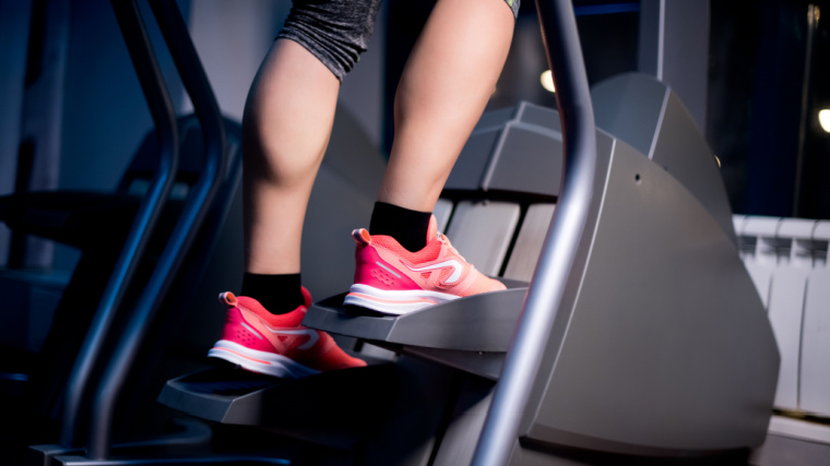 Legs of a girl who is engaged in a stepping machine in the gym.