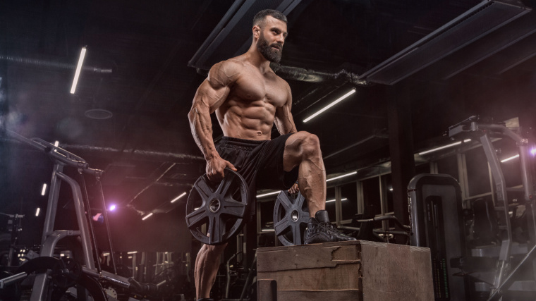 A muscular person lifting weight plates in the gym.