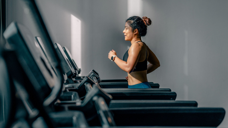 Individual jogging on treadmill at gym, promoting fitness and a healthy lifestyle.