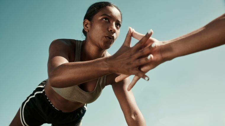 An athlete holds a plank position while tapping another athlete's hand.